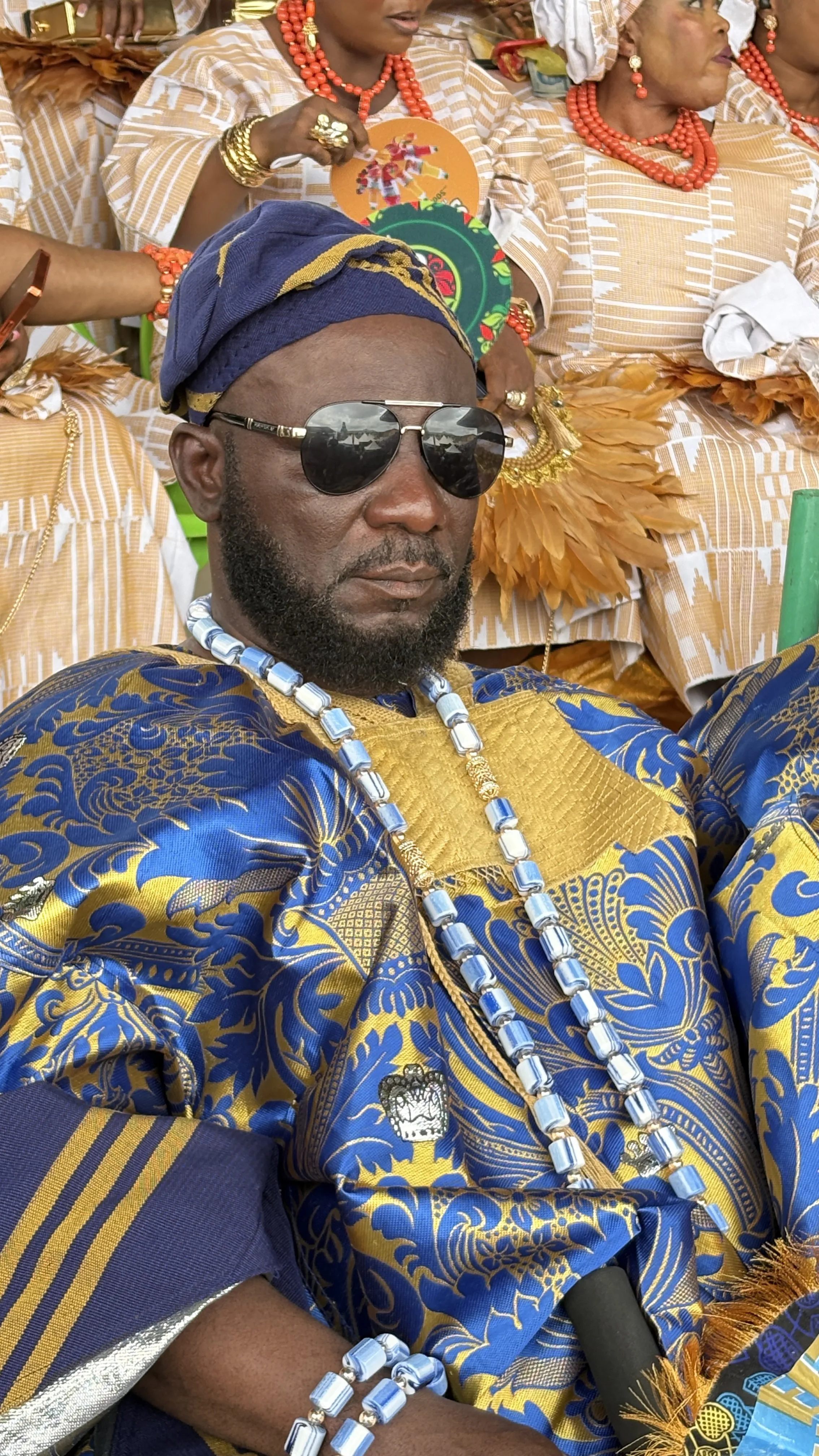 Man in blue and gold agbada with fila, sunglasses and beaded jewellery at Ojude Oba 2026